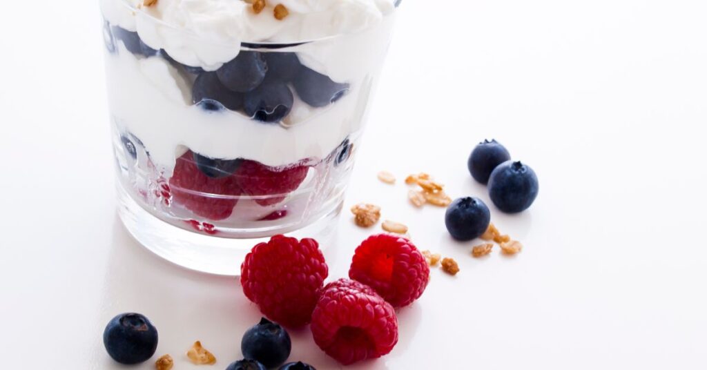 Glass jar layered with Greek yogurt, strawberries, blueberries, and banana slices, zero point parfait