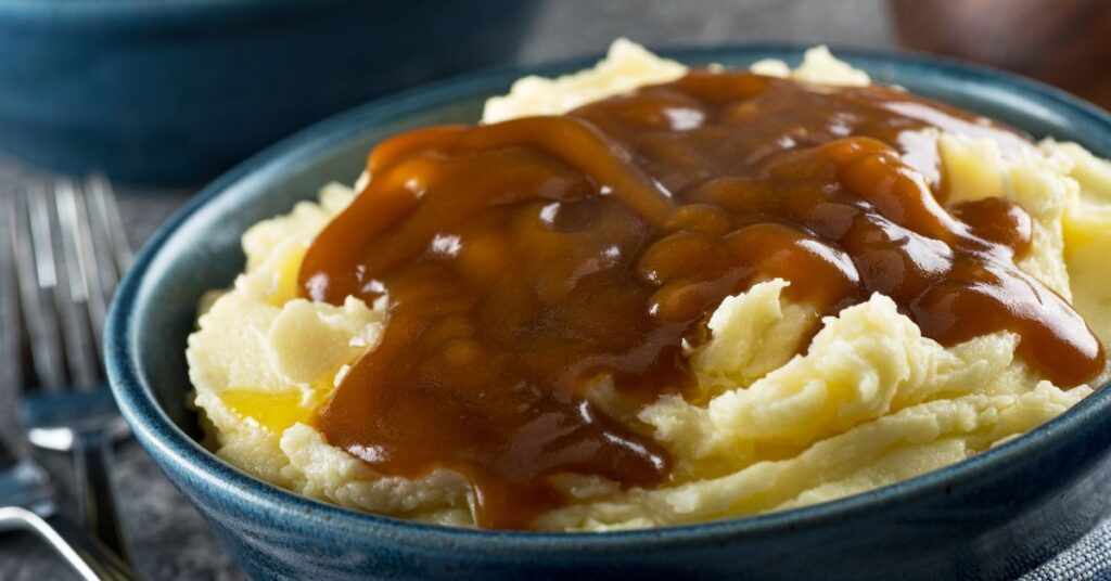 Creamy mashed potatoes topped with low-point gravy in a blue bowl.