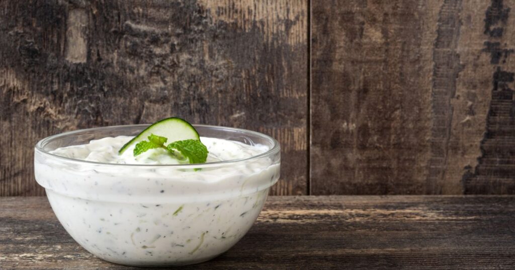 Bowl of creamy cucumber yogurt dip with fresh dill and cucumber slices, Weight Watchers friendly